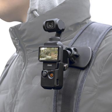A compact camera mounted on a shoulder strap, facing forward.